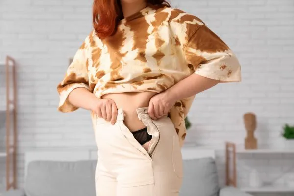 Image of woman trying to do her trousers up after pregnancy weight gain Chinnor