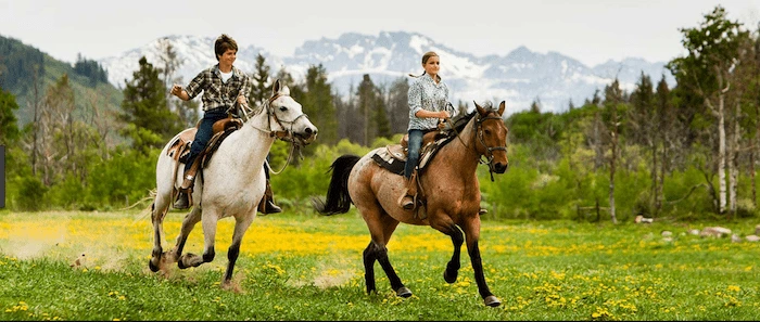 Confident plus-size woman riding Chinnor a horse through a field with a smile on her face.